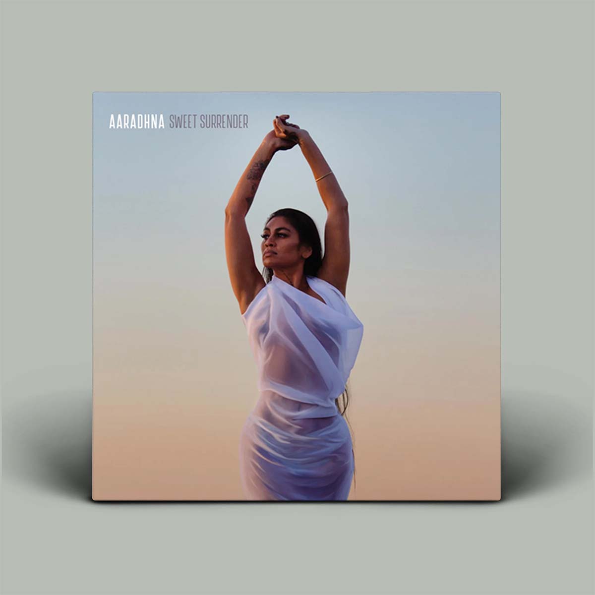 Album cover with a person in a white dress against a gradient background, featuring the text 'Aaradhna Sweet Surrender'.