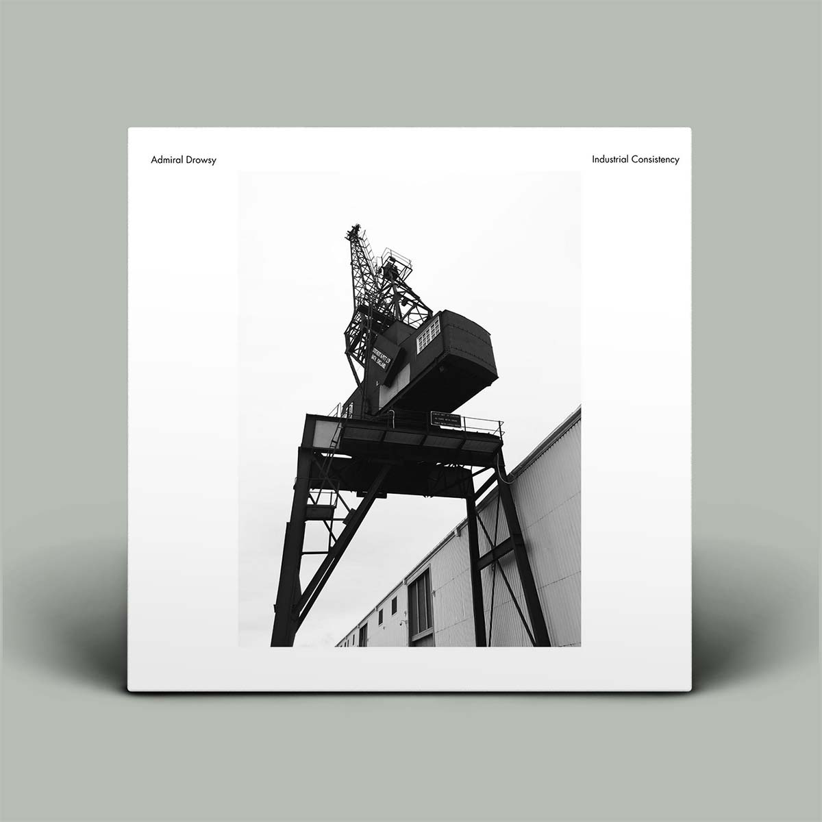 Album cover with a black and white photograph of an industrial structure on a gray background