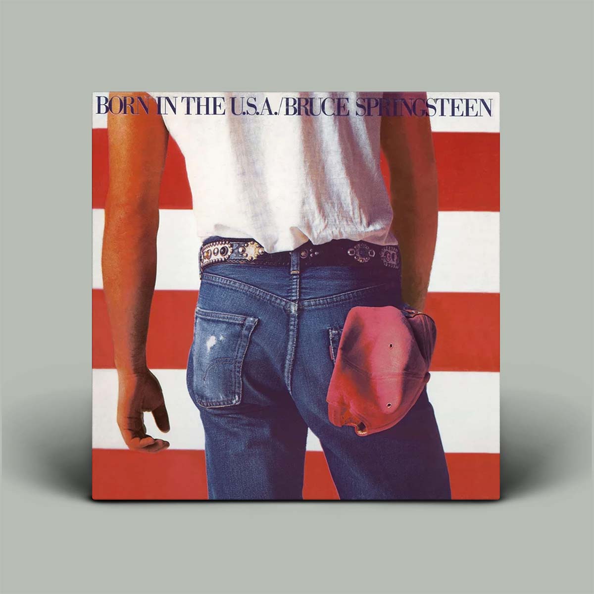 Vinyl album cover of 'Born in the USA' by Bruce Springsteen with a person wearing jeans and a cap against an American flag background.