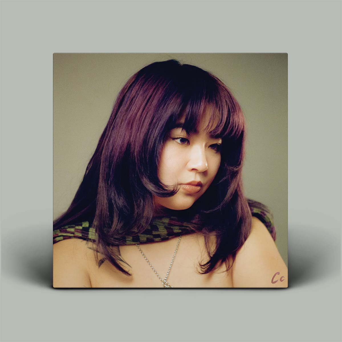 Square portrait of a person with long hair against a plain background