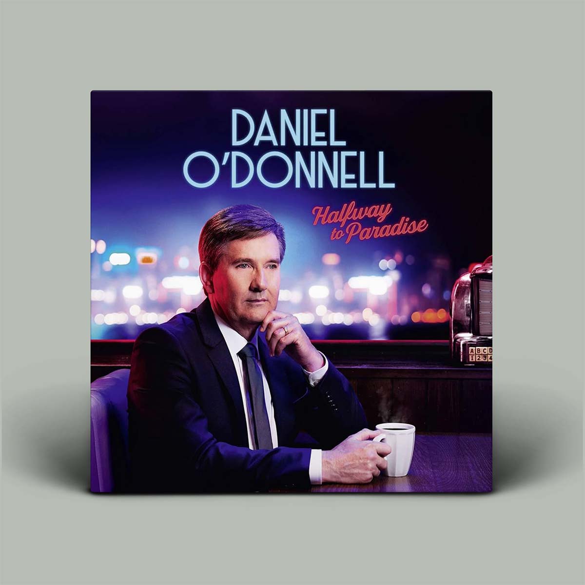 Album cover for Daniel O'Donnell's 'Halfway to Paradise' with a man sitting at a table holding a cup.
