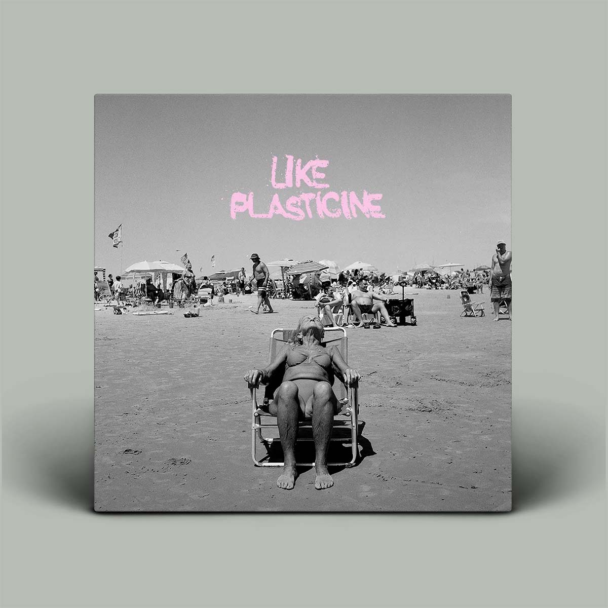 Album cover with black and white beach scene and pink text 'LIKE PLASTICINE'.