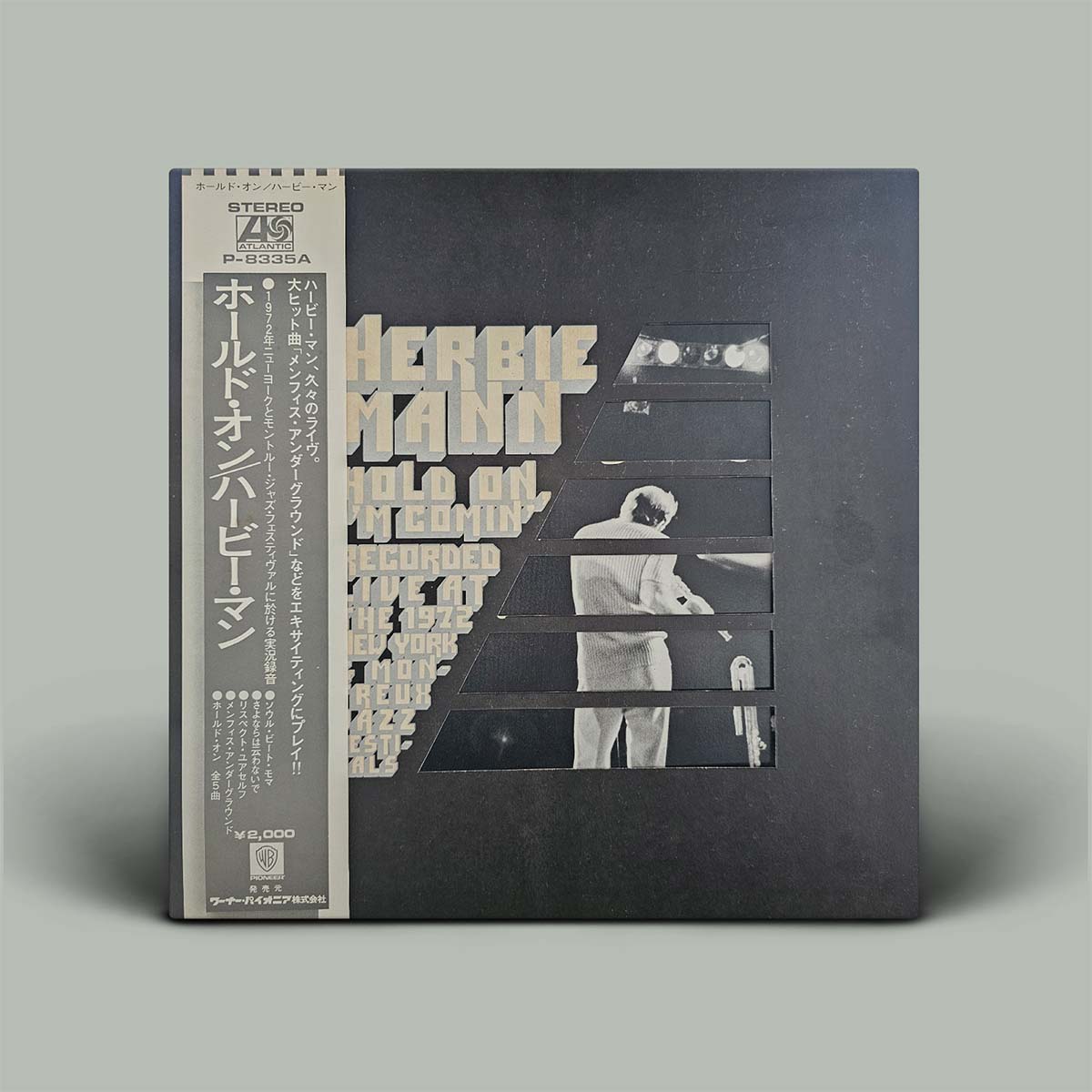 Vinyl record with a black cover featuring cut-out images and text on a gray background