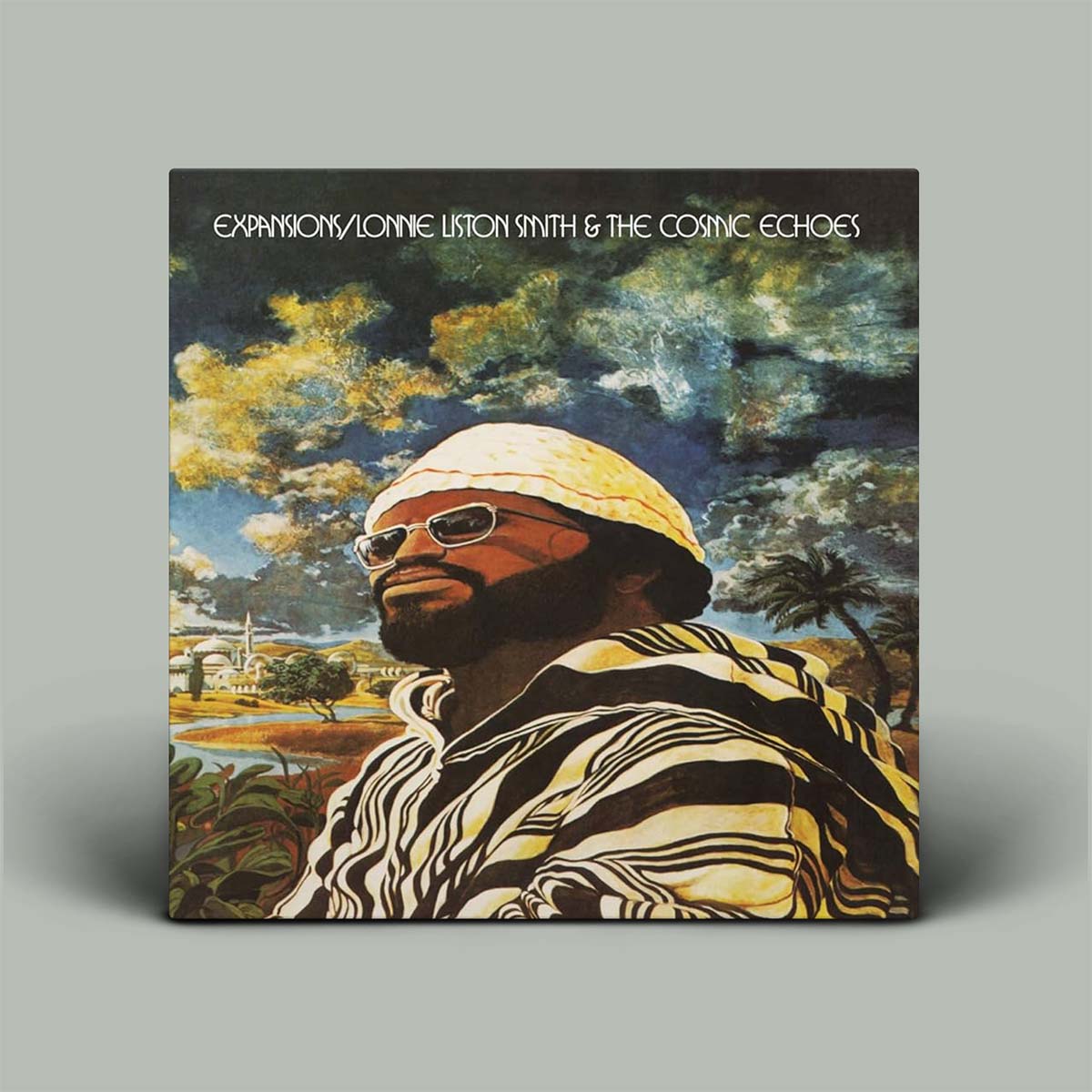 Album cover with a person wearing sunglasses and a hat, set against a scenic background.