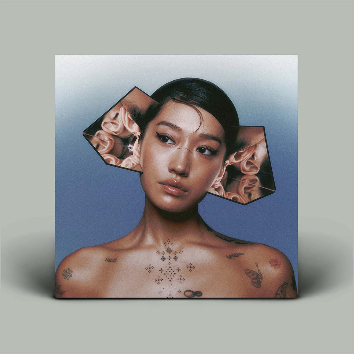 Album cover with a person's neck and tattoos, surrounded by images of ears and flowers on a gradient background.