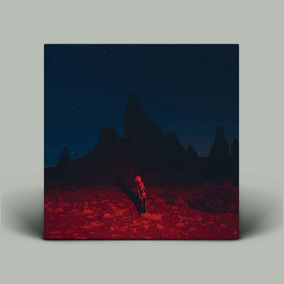 Surreal landscape with a red figure sitting under a dark blue sky.