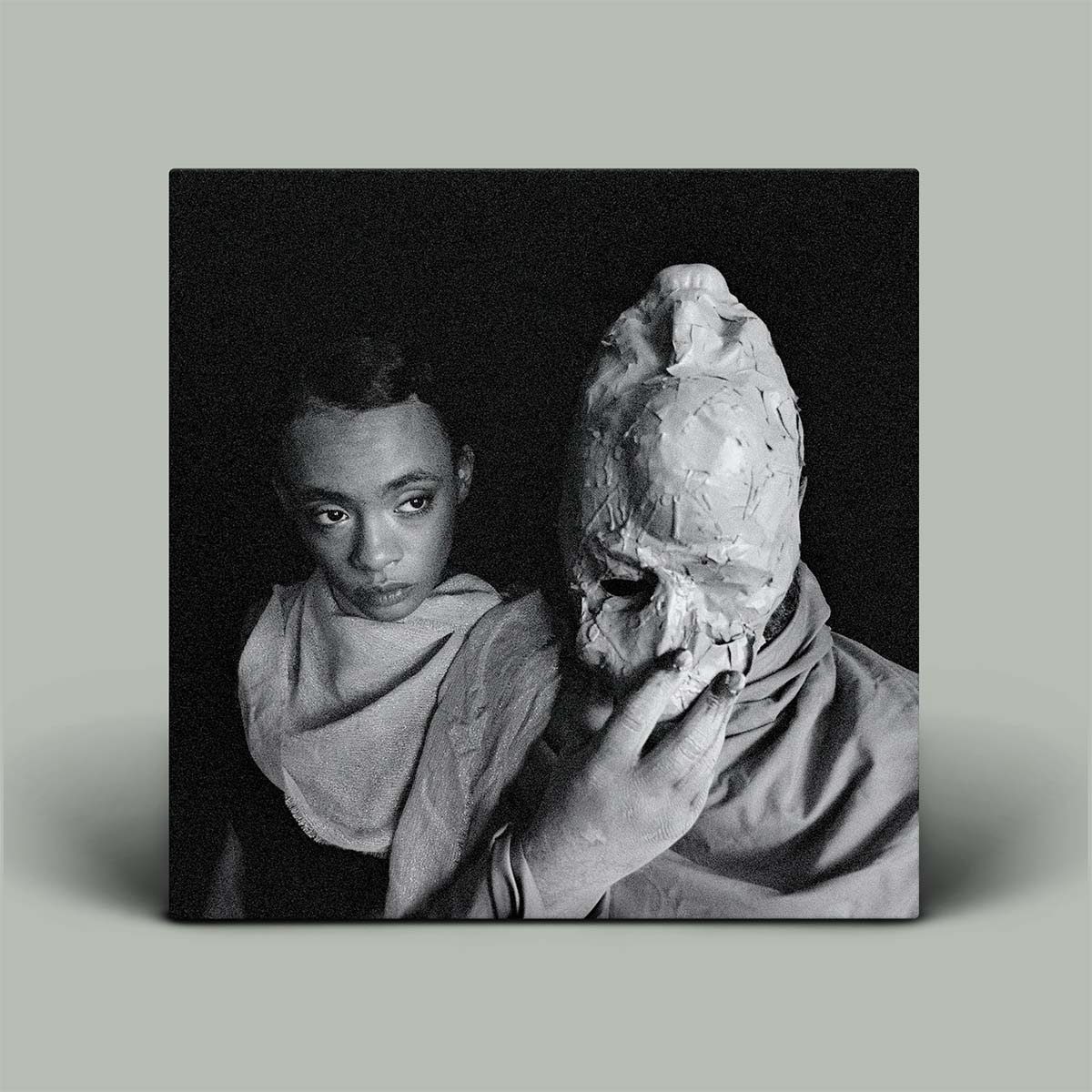 Album cover photograph of a person holding a skull against a black background