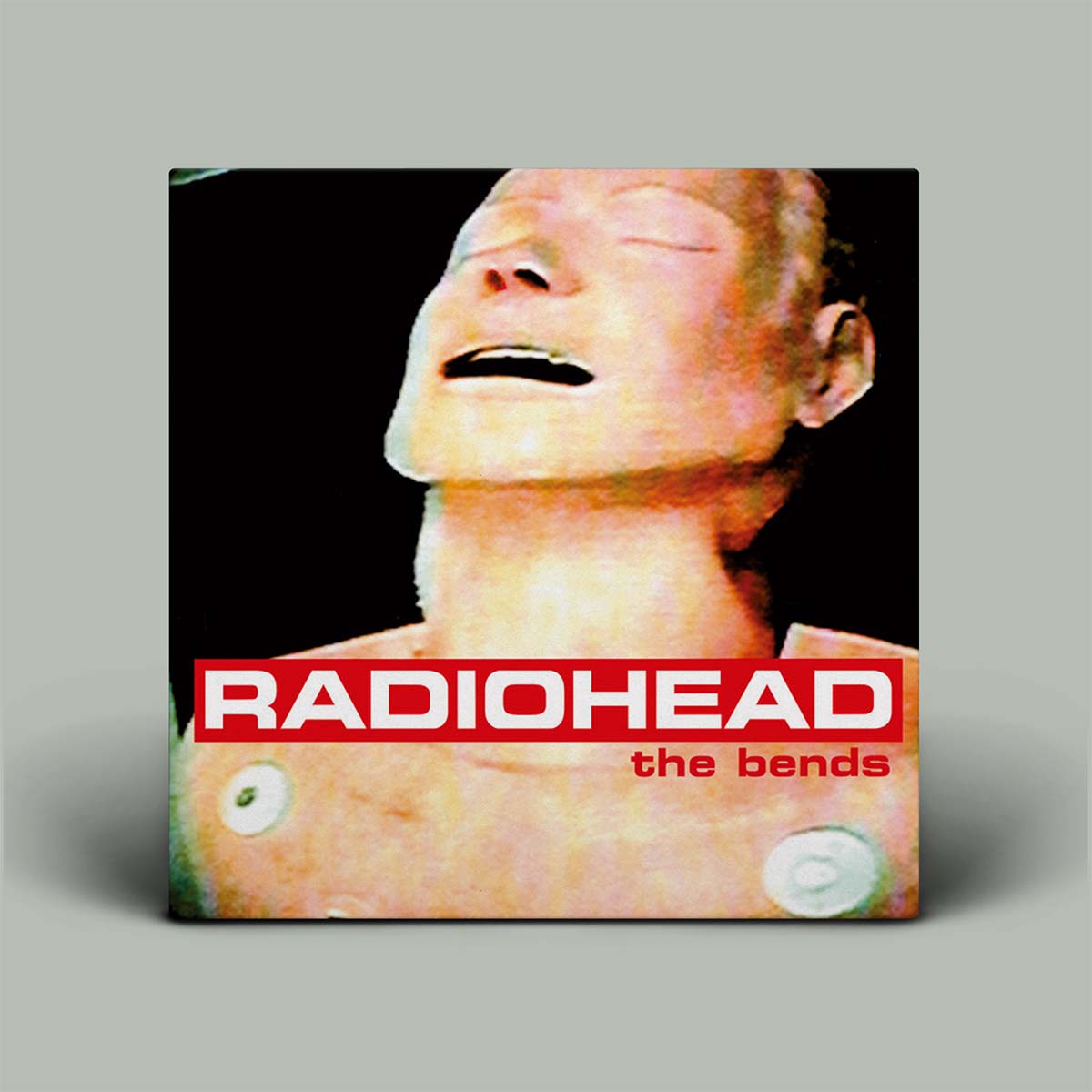 Album cover for Radiohead's The Bends featuring a close-up photograph of a human head with the band's name and album title text in red.