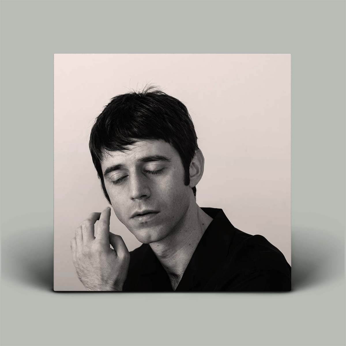 Album cover with a black and white portrait of a person on a light pink background