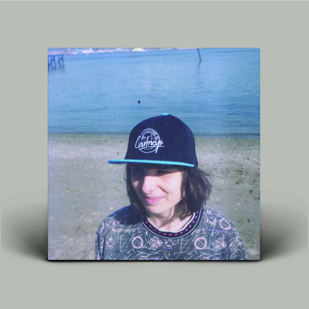 Person wearing a blue cap with a logo, standing in front of a body of water.