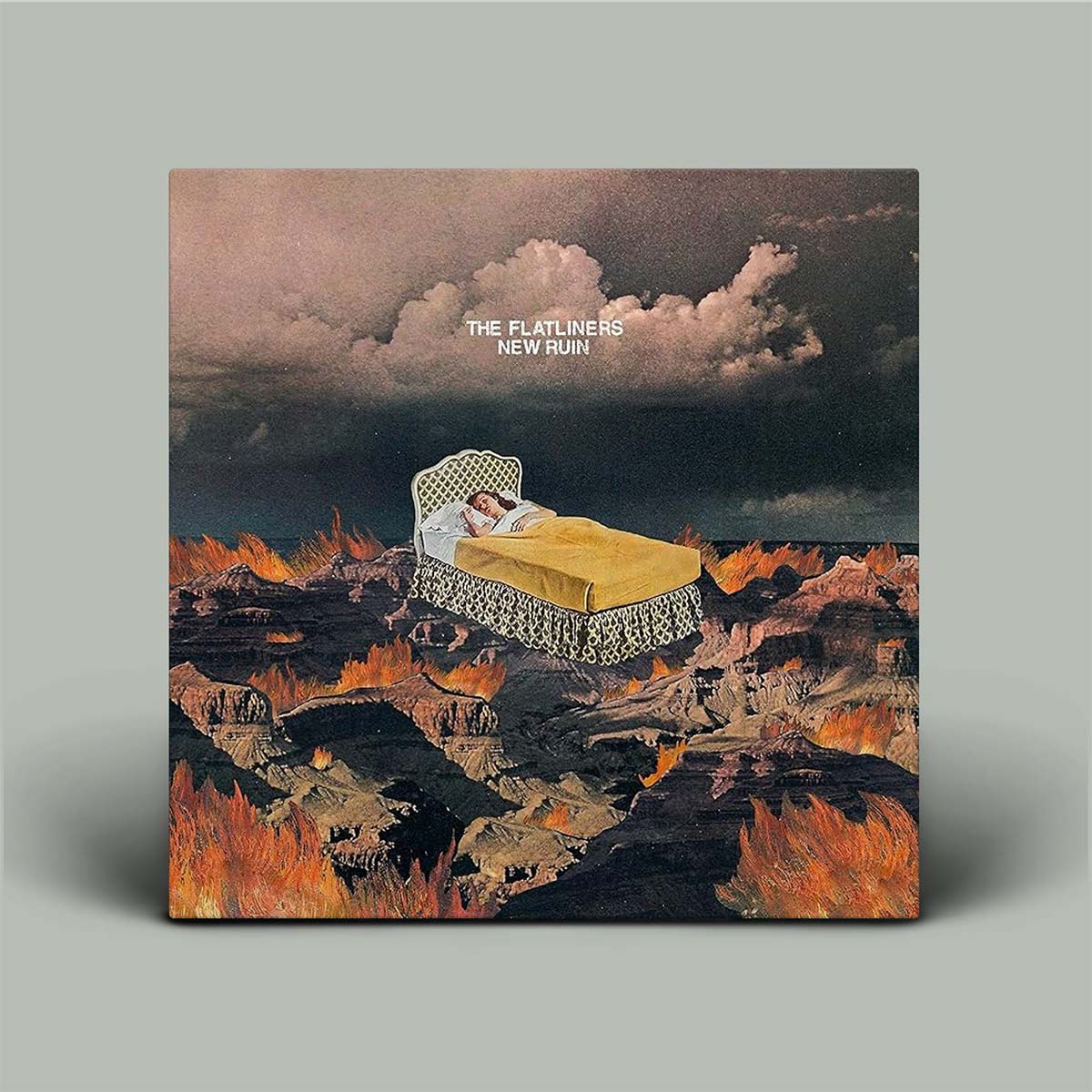 Album cover with a person in bed amidst flames and clouds, titled 'The Flatliners New Ruin'.