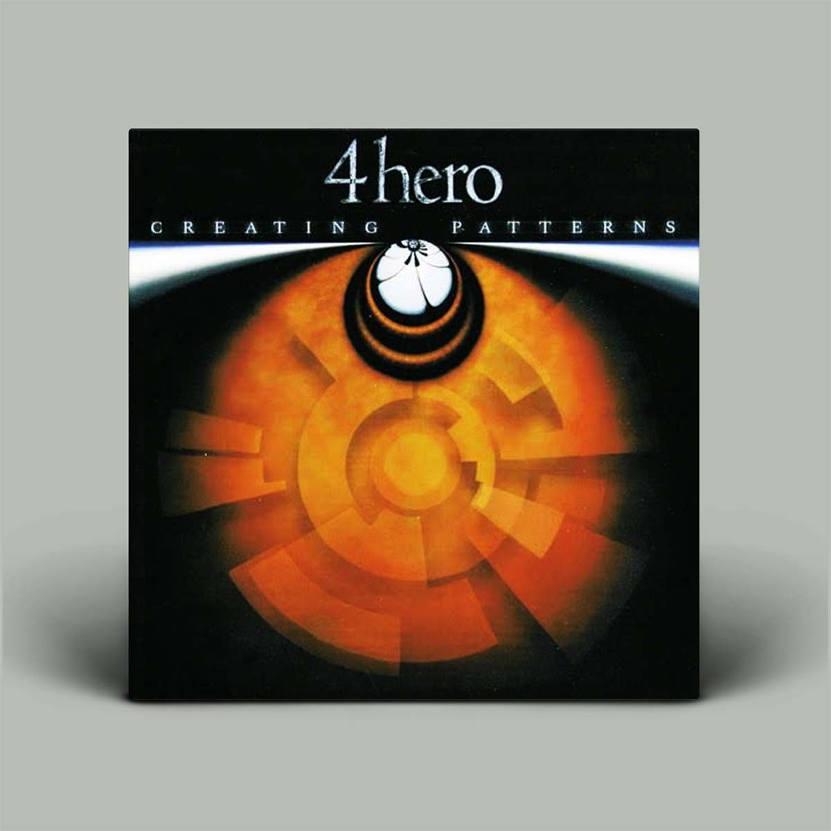 A square album or book cover standing upright on a light gray background. The cover is predominantly black with a large orange and yellow abstract circular design and the text '4 hero' and 'CREATING PATTERNS' at the top.