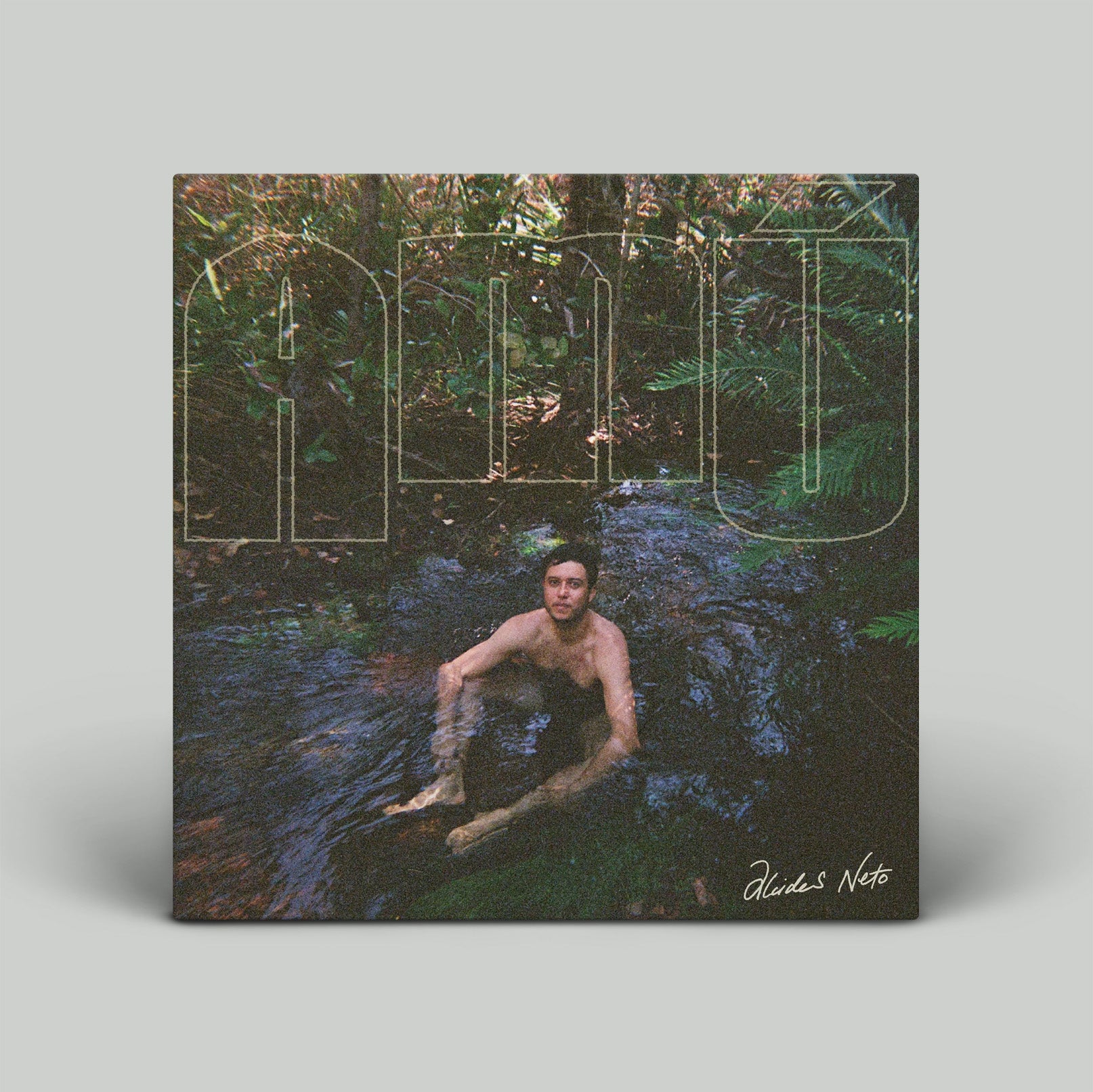 Album cover with a person sitting by a stream in a forest setting