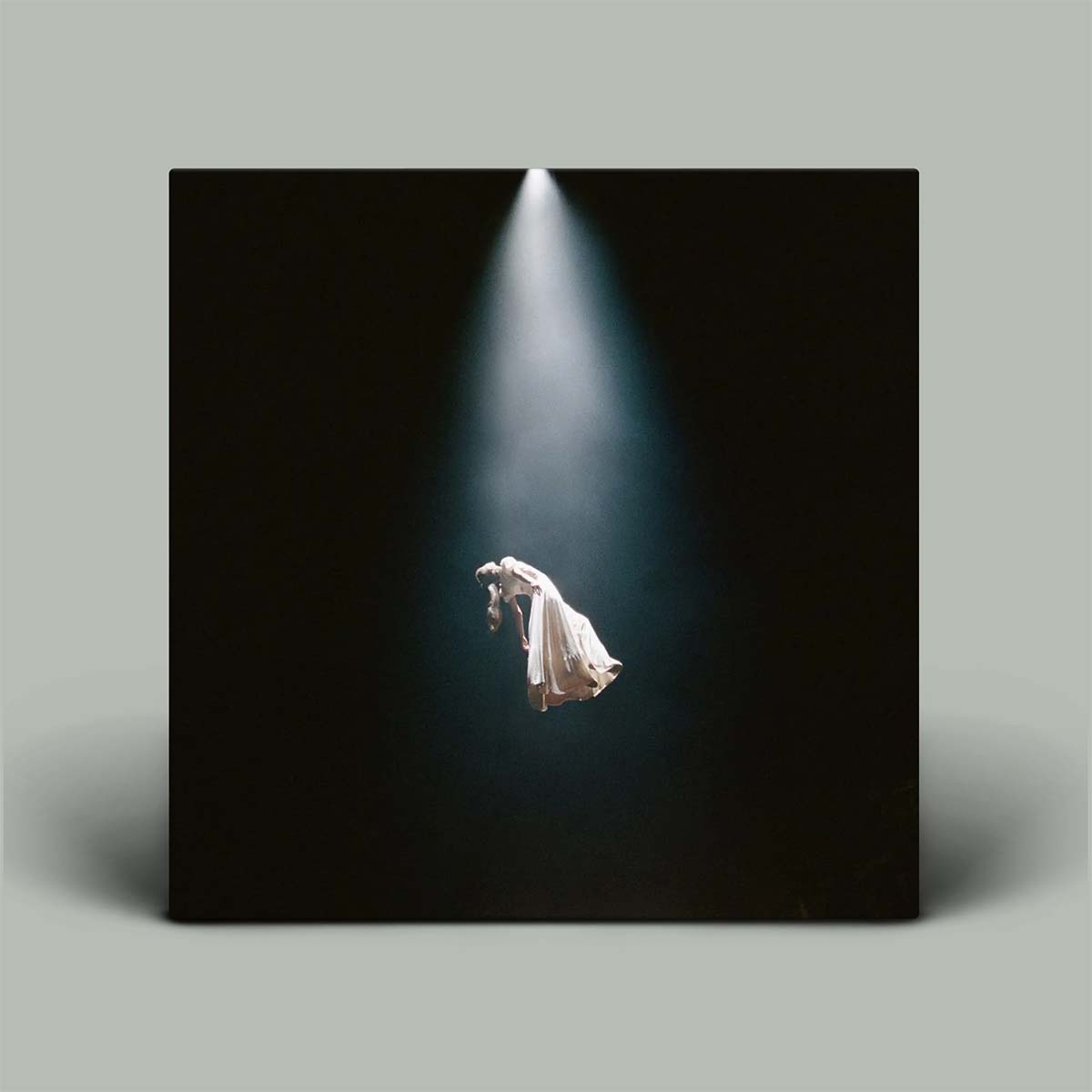 Person in a white dress floating in a spotlight on a black background