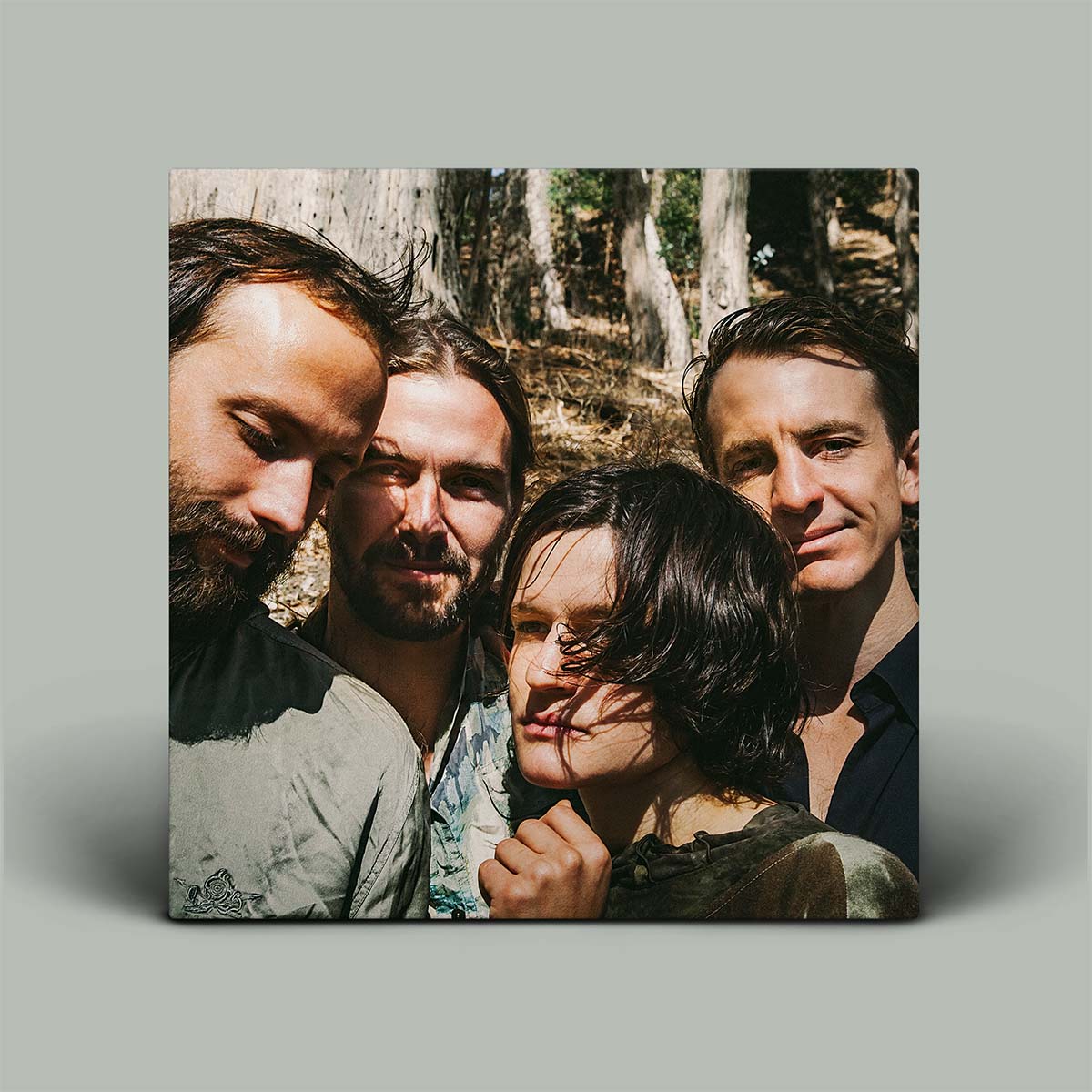 Four people standing close together with a forest background