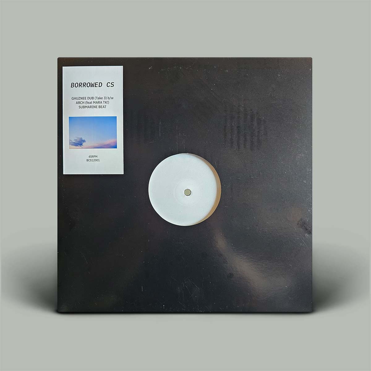 Vinyl record with a dark cover and white label on a gray background