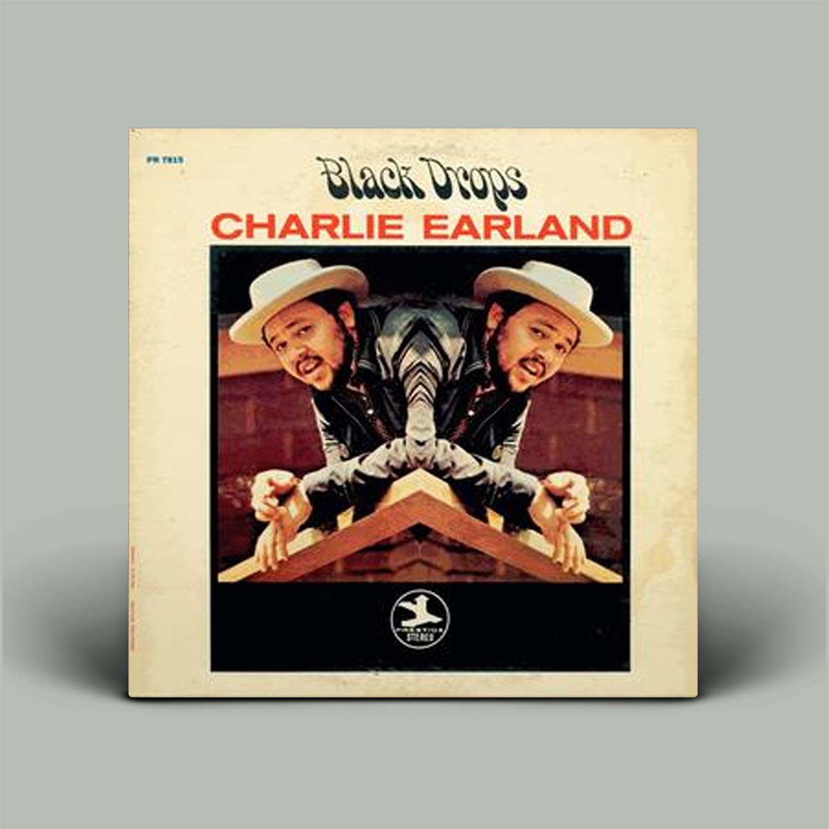 Charlie Earland's 'Black Drops' vinyl record album cover, featuring a cream-colored border and a central mirrored photograph of the artist in a white hat and dark jacket, set against a solid gray background.
