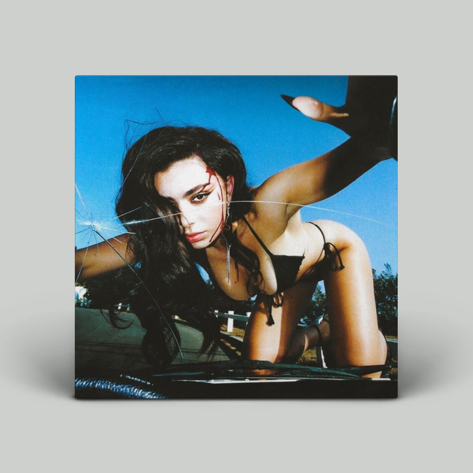 Album cover with a person in a bikini on a car, against a blue sky.
