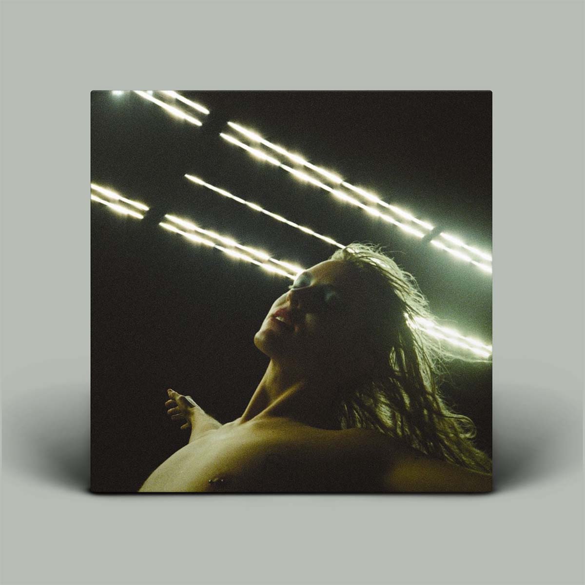 Person with long hair and arms wide against a dark background with light streaks