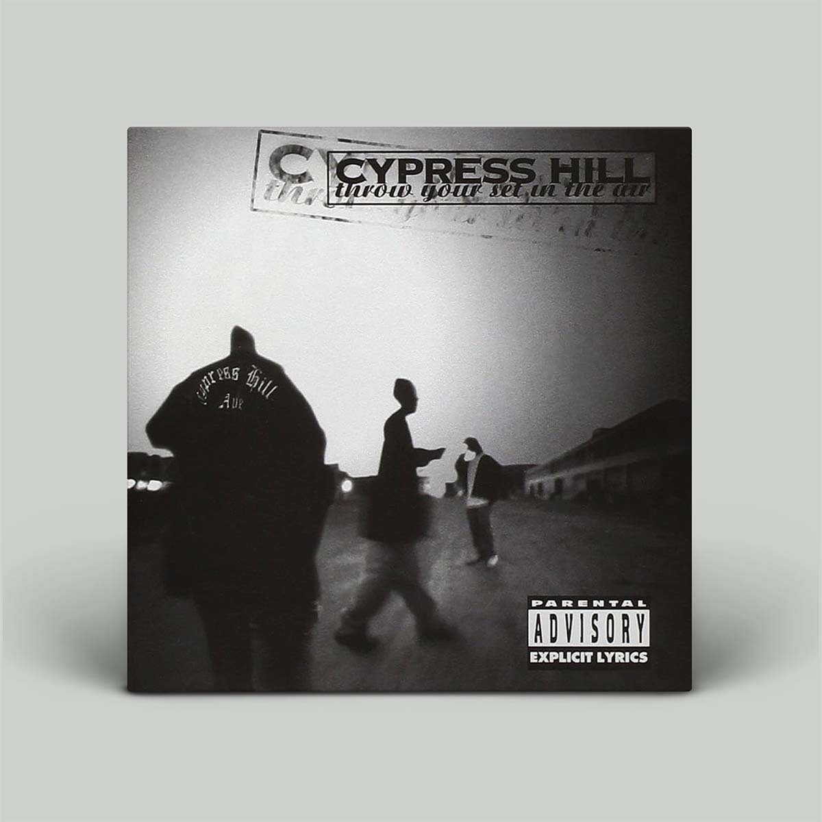 A square black-and-white album cover for Cypress Hill's 'Throw Your Set in the Air' is shown standing upright against a light gray background. The cover features silhouetted figures walking in a street scene, with the Cypress Hill logo and a Parental Advisory label visible.