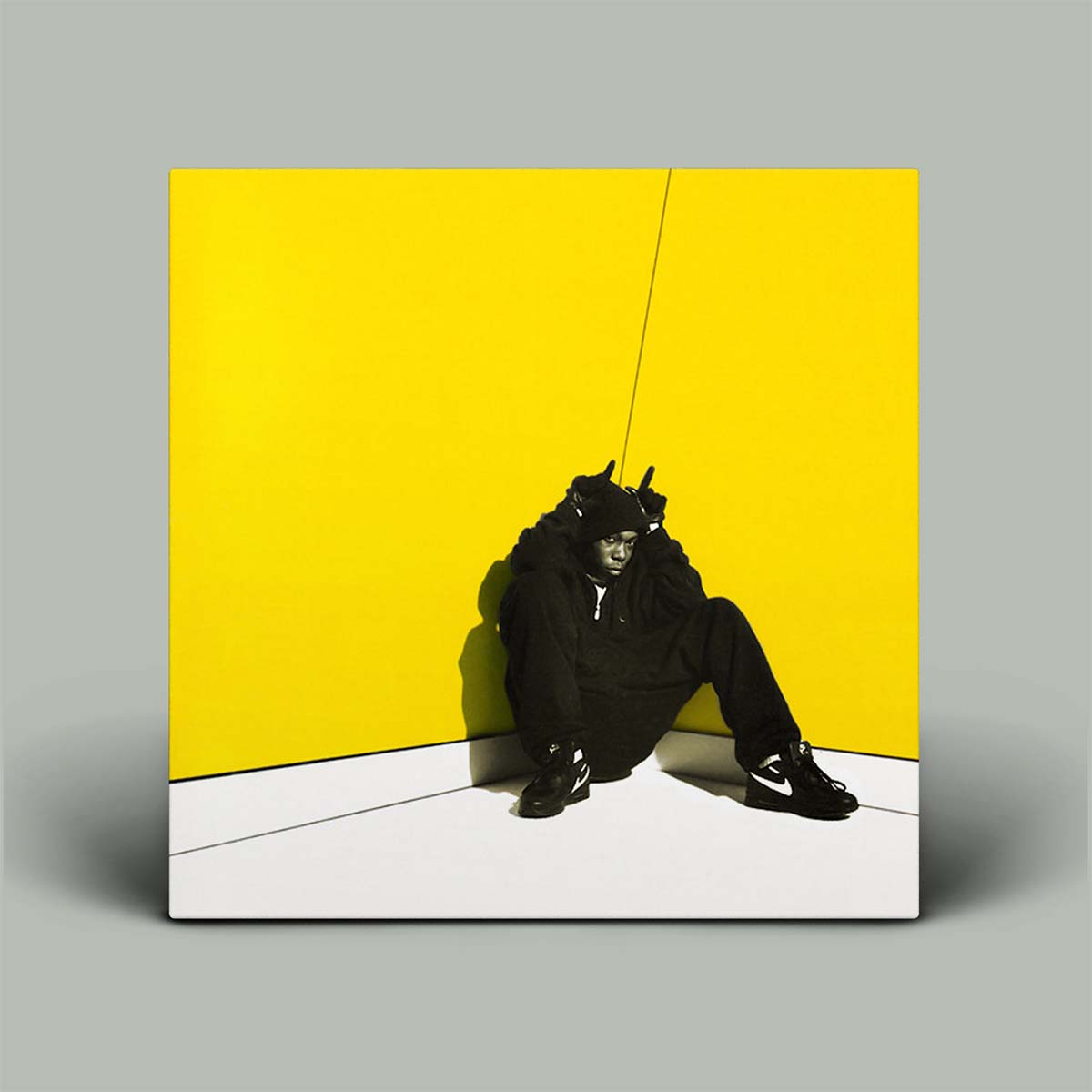 Person in black outfit against a yellow wall with a white floor
