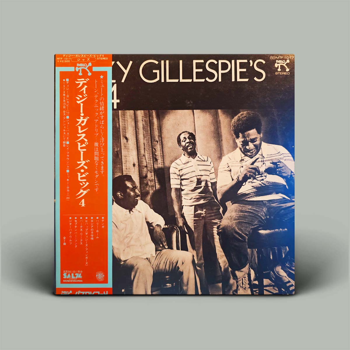 Vinyl record cover featuring a black and white photo of three men with text on an orange background.