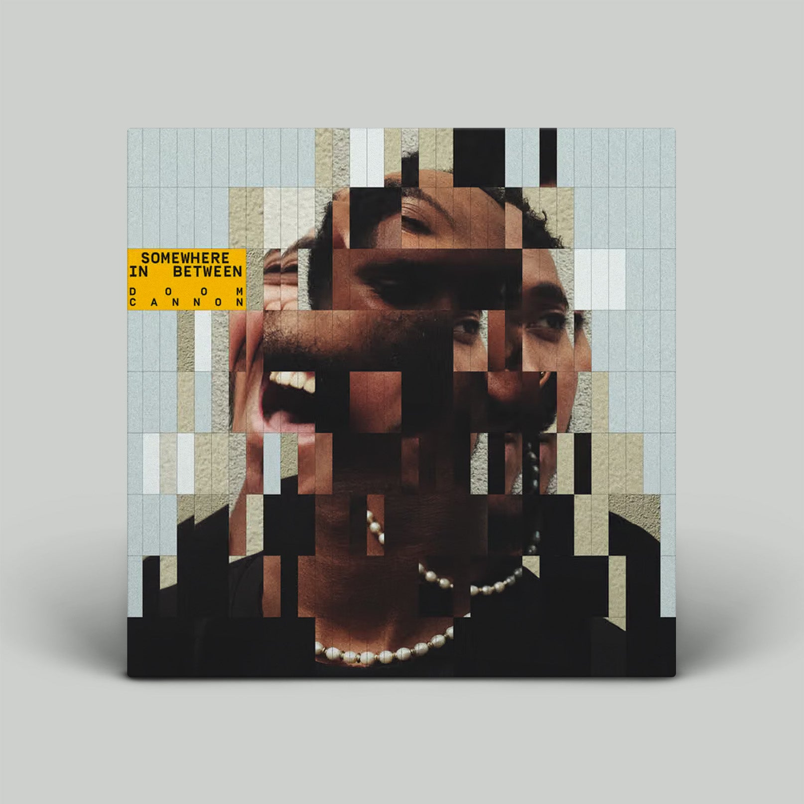 Album cover with a mosaic design featuring a person's face and text on a gray background