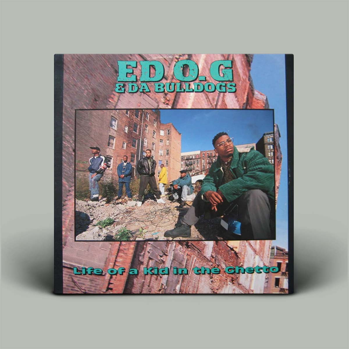 Album cover of 'ED O.G & Da Bulldogs - Life of a Kid in the Ghetto' featuring a man sitting with a group of people in the background against an urban backdrop.