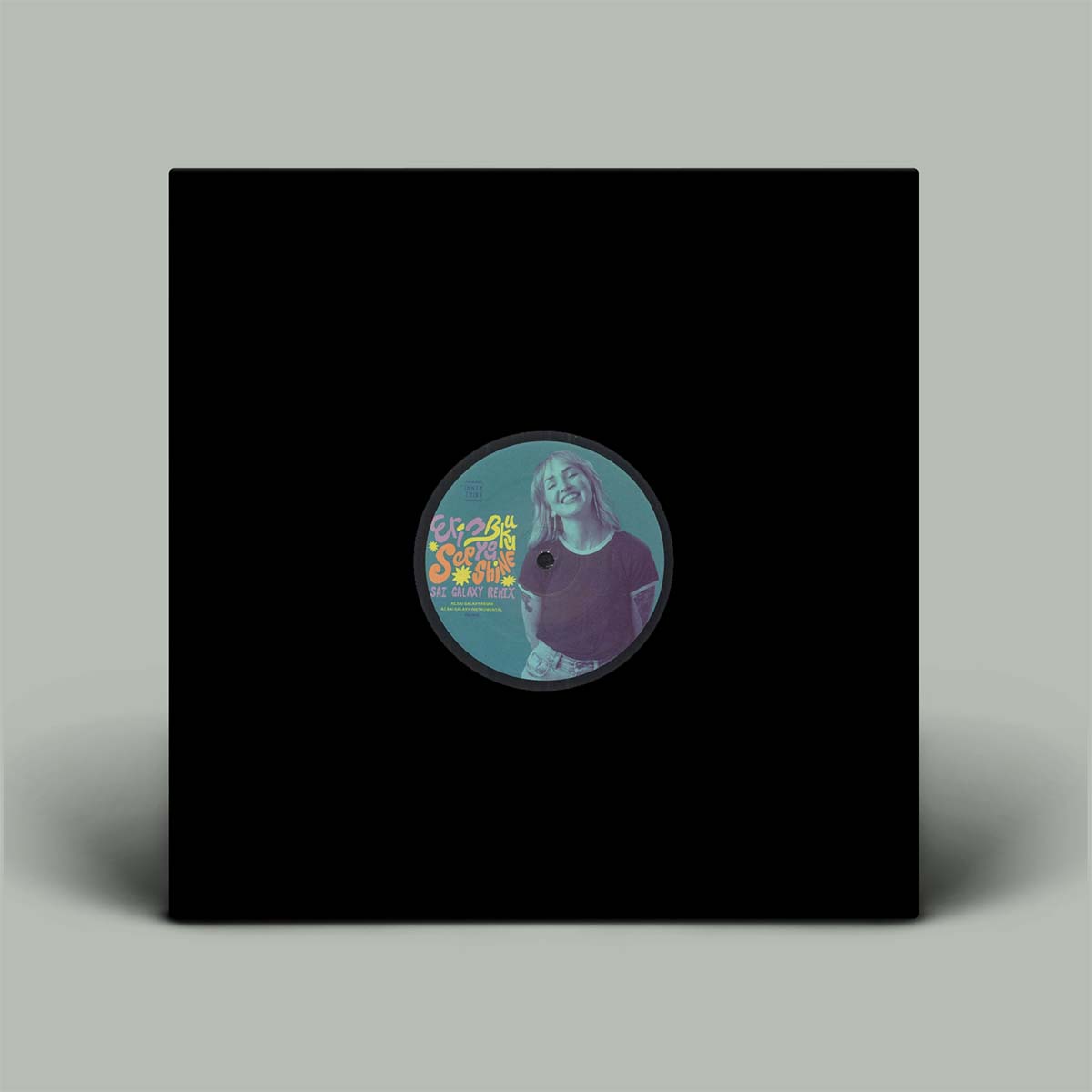 A square black vinyl record sleeve or album cover standing upright on a light gray background, with a circular label in the center showing a stylized portrait and colorful text.