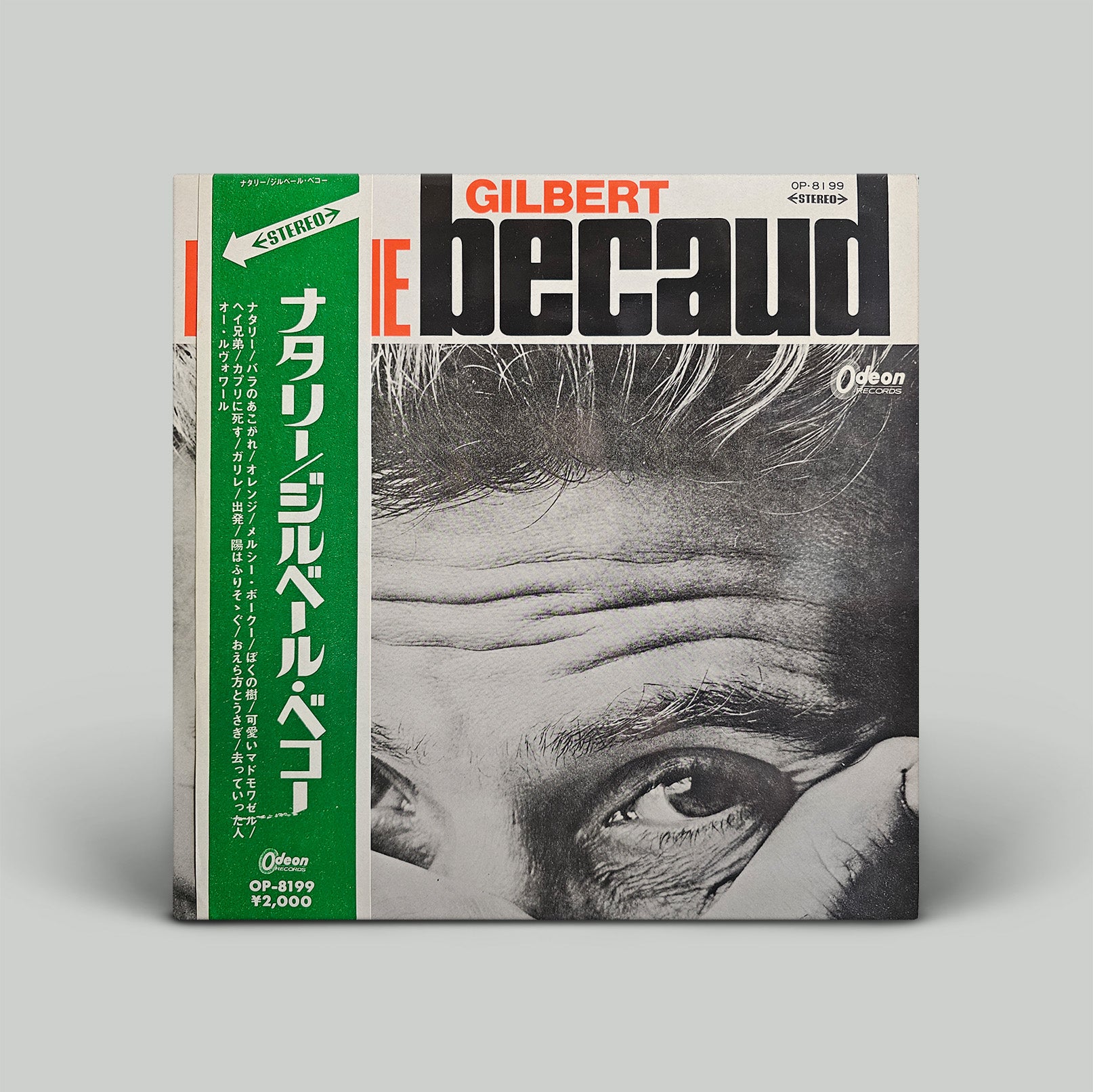 Album cover with a close-up of a person's eye and hair, featuring the text 'Gilbert Becaud' on a gray background.