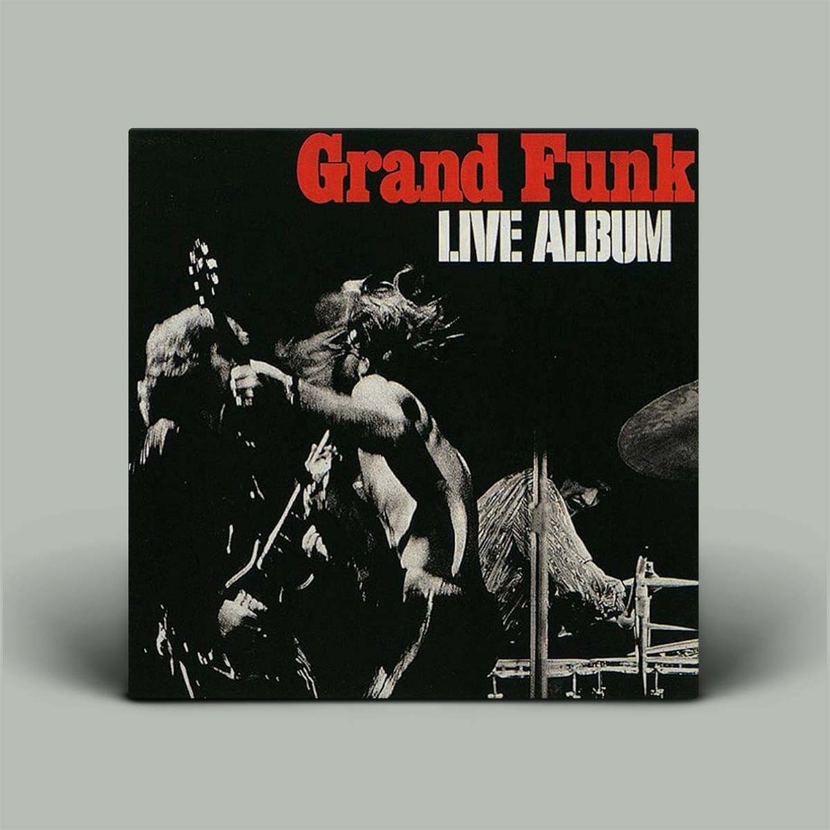 The image displays the album cover of "Live Album" by Grand Funk Railroad. The cover features a dramatic black and white photograph of the band performing, with intense expressions and dynamic poses, reflecting the energy of their live performances.