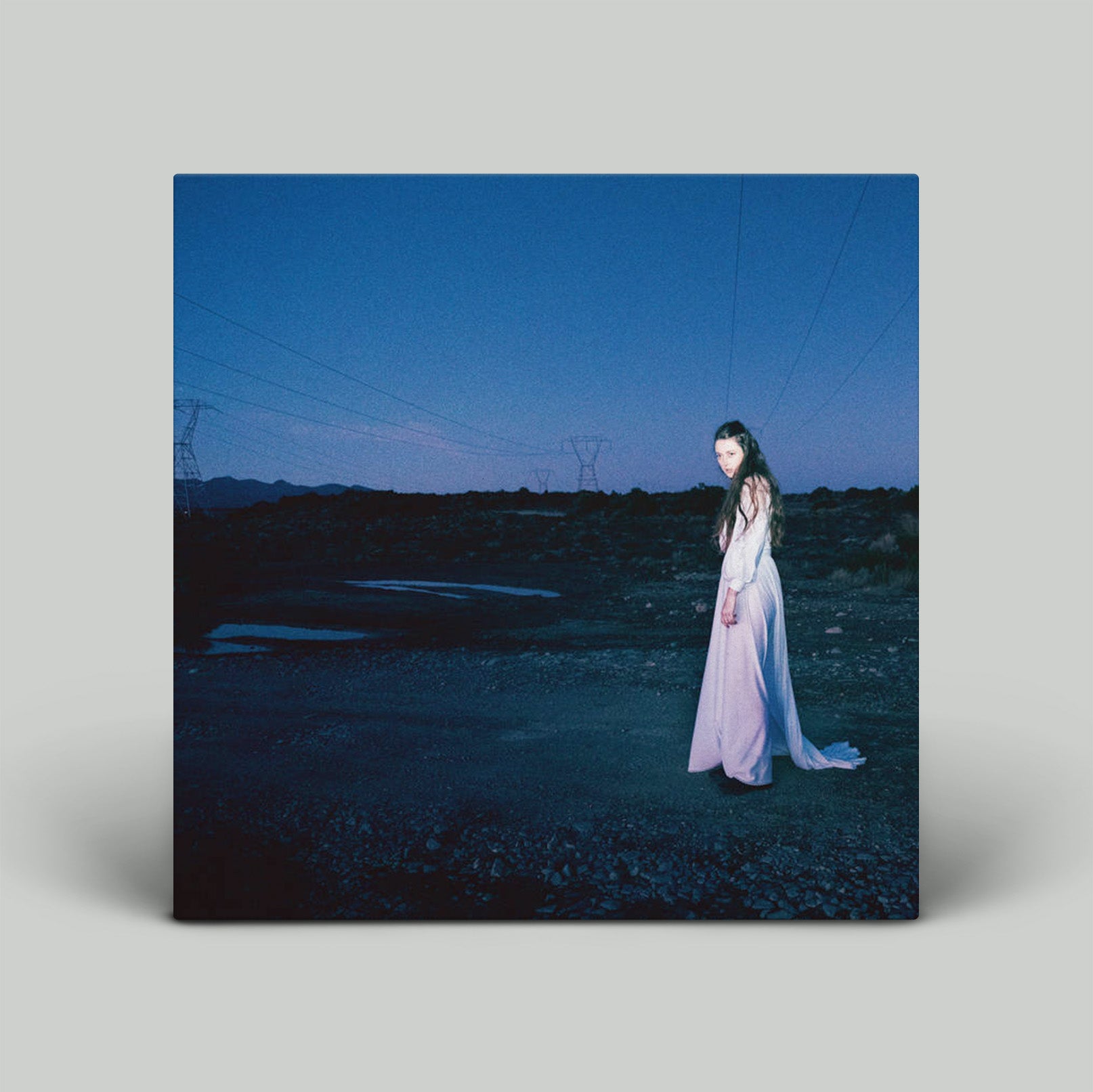 Album cover with a person in a white dress standing in a field at night.