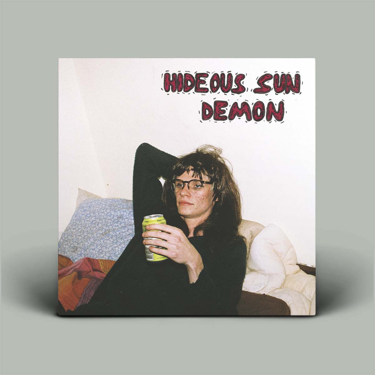 Album cover with a person holding a drink, text 'Hideous Sun Demon' at the top, on a gray background