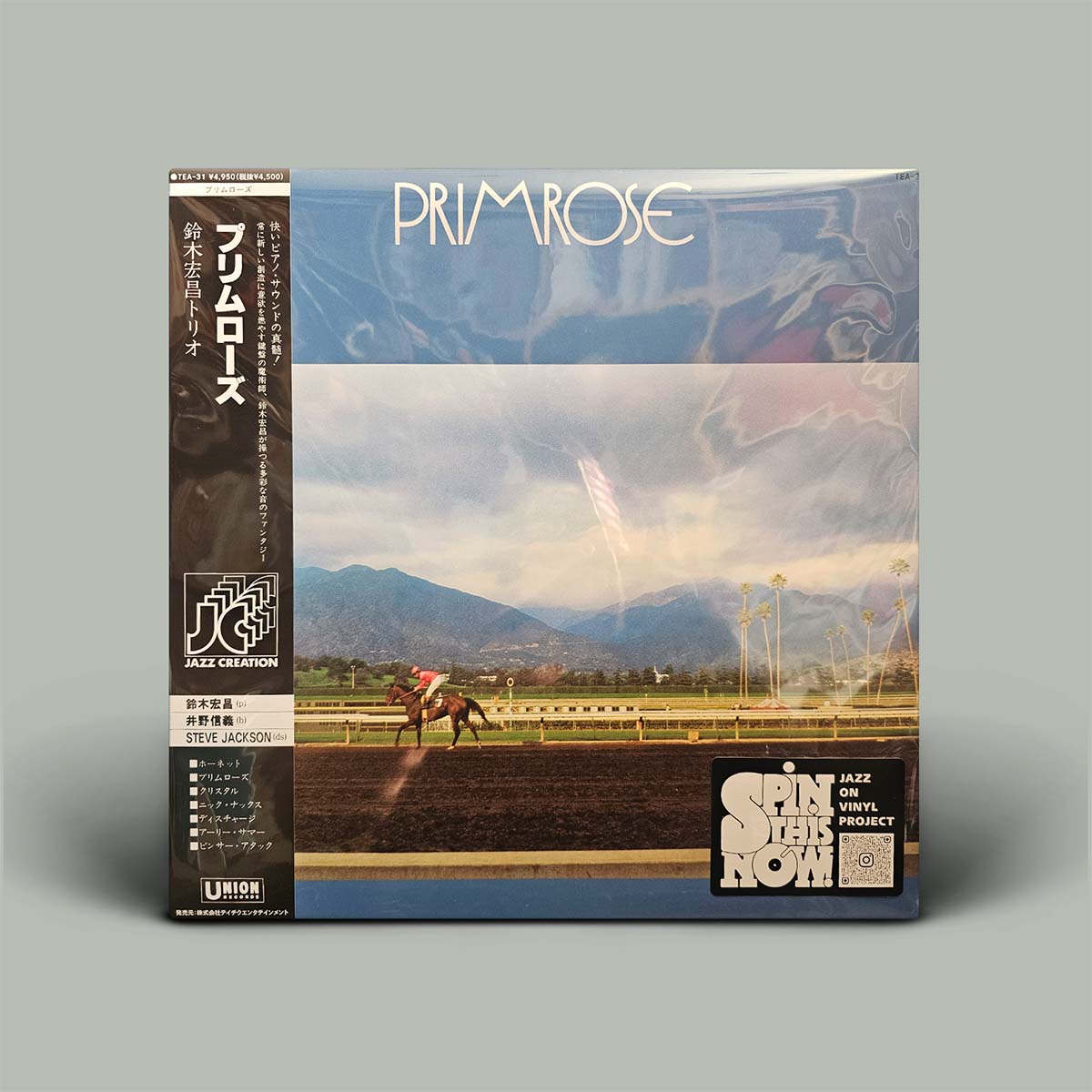 A vinyl record sleeve for Primrose album, shown in its shrink wrap on a solid gray background.