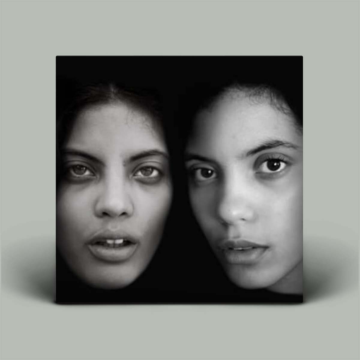 A black and white album cover featuring two young women looking directly at the camera, with the album title 'Ibeyi' printed at the top.