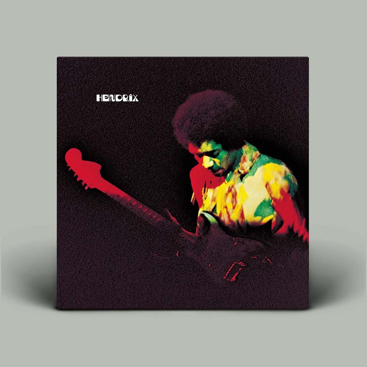A square album cover for Hendrix stands upright against a light gray background. The cover art features a grainy, high-contrast portrait of Jim Morrison playing an electric guitar in red, yellow, green, and black tones, with the white text 'HENDRIX' in the upper left.