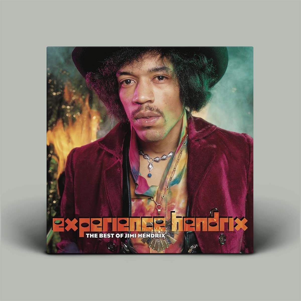 Album cover for 'Experience Hendrix: The Best of Jimi Hendrix' displayed as a square print or sleeve against a light gray background. The cover features a portrait of Jimi Hendrix wearing a black hat and a burgundy velvet jacket over a tie-dye shirt, with orange title text at the bottom.
