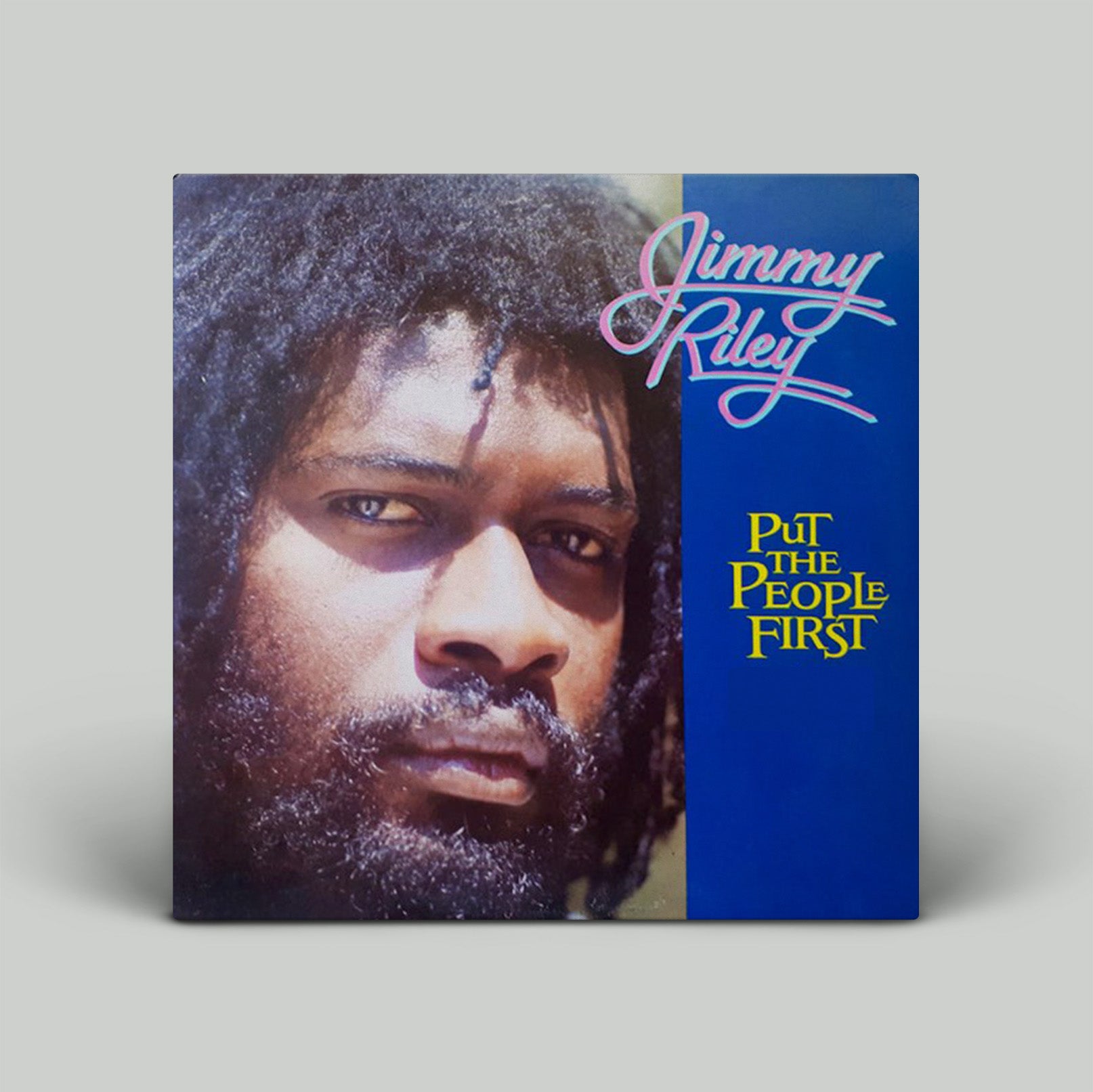 Vinyl record cover with a person's face and 'Jimmy Riley Put the People First' text on a blue background