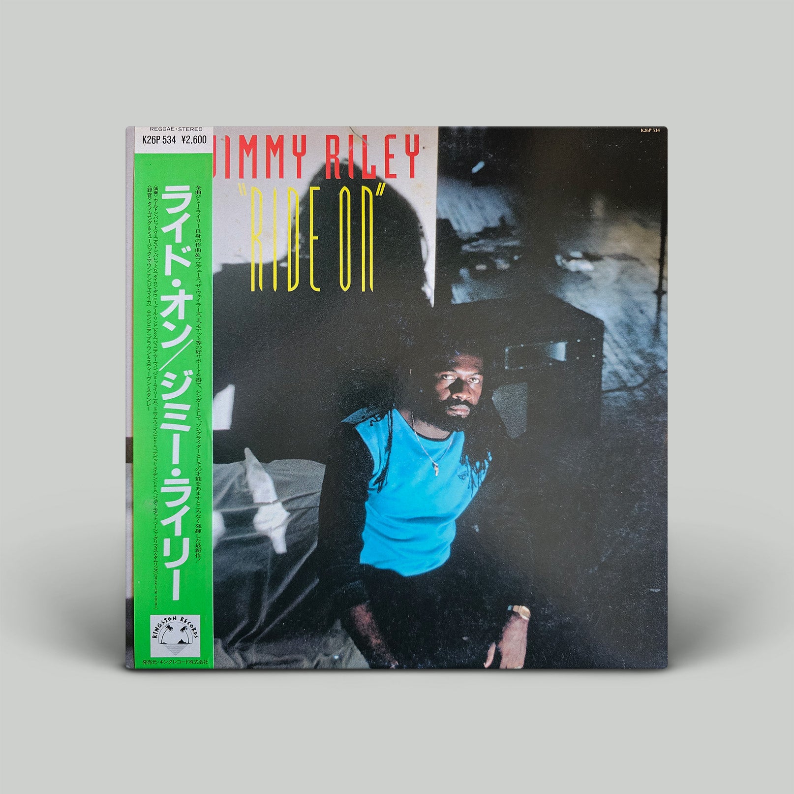 Vinyl record cover with a person in a blue shirt and text 'Jimmy Riley Ride On' on a gray background