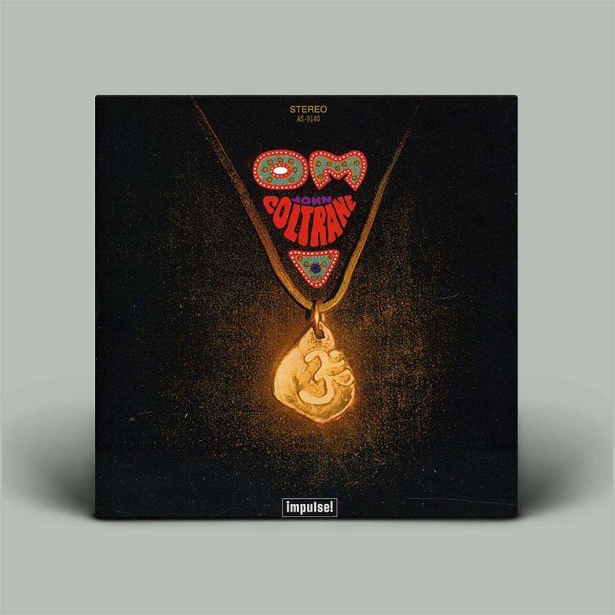 Vinyl record cover with a necklace pendant and 'John Coltrane' text on a dark background