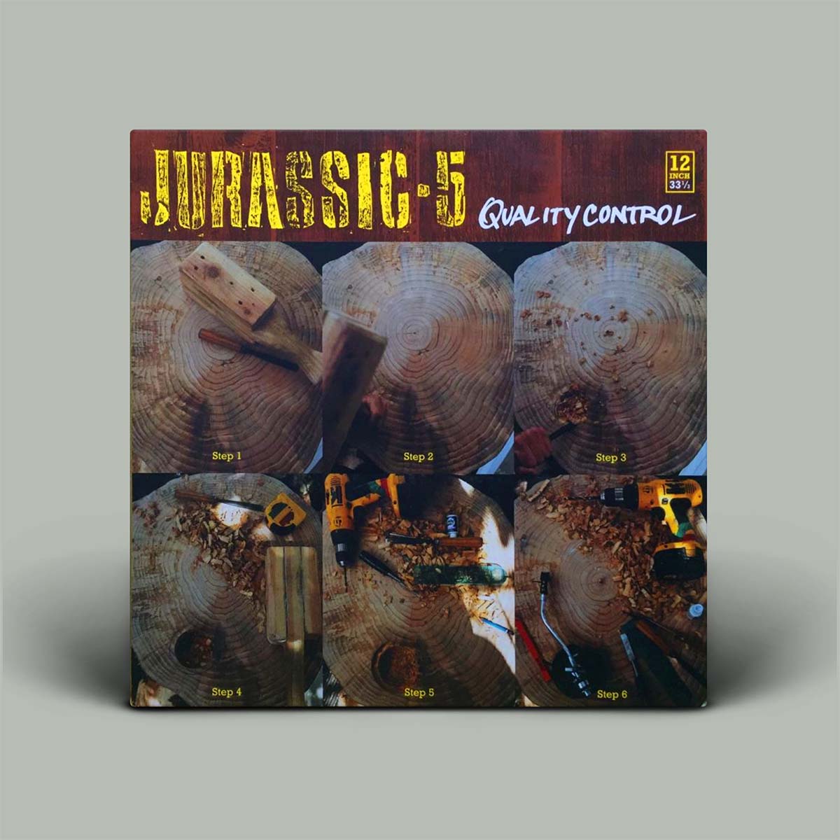 Album cover titled 'JURASSIC 5 Quality Control' stands upright on a light gray background. The cover shows six photos of wood grain and drilling, with yellow and white text and a small text mark in the top right.