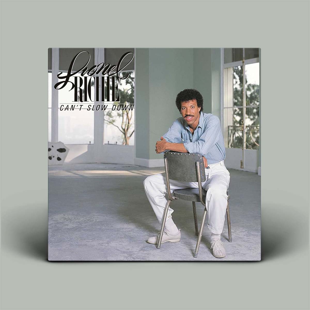 Album cover featuring a man sitting on a chair with 'Lionel Richie' and 'Can't Slow Down' text.