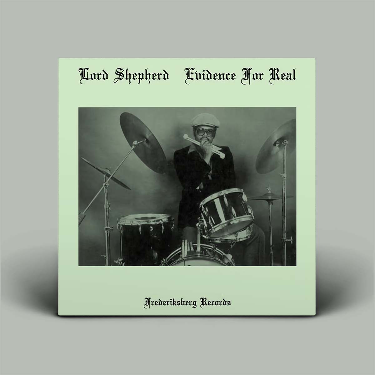 A square album cover for 'Evidence For Real' by Lord Shepherd, released on Frederiksdberg Records. The cover features a pale mint green background with a central black-and-white photograph of a man playing drums.