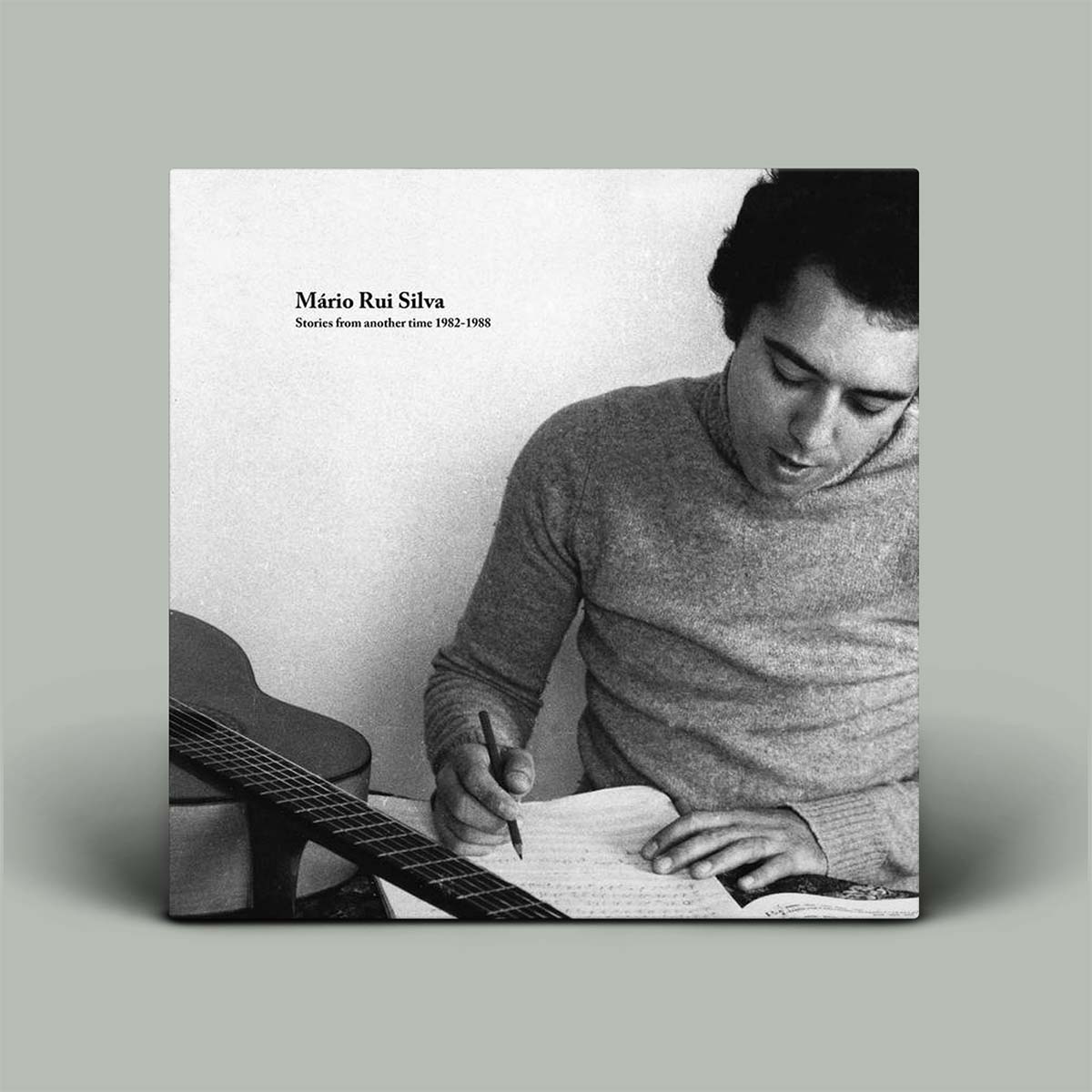 Album cover with a black and white photo of a man playing guitar and writing music notes, with text 'Môrio Rui Silva' on a gray background.
