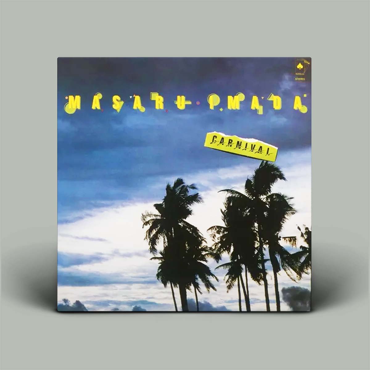 A vinyl record sleeve for 'Carnival' album, featuring a tropical scene with palm trees against a cloudy blue sky and yellow stylized text, displayed on a neutral gray background.
