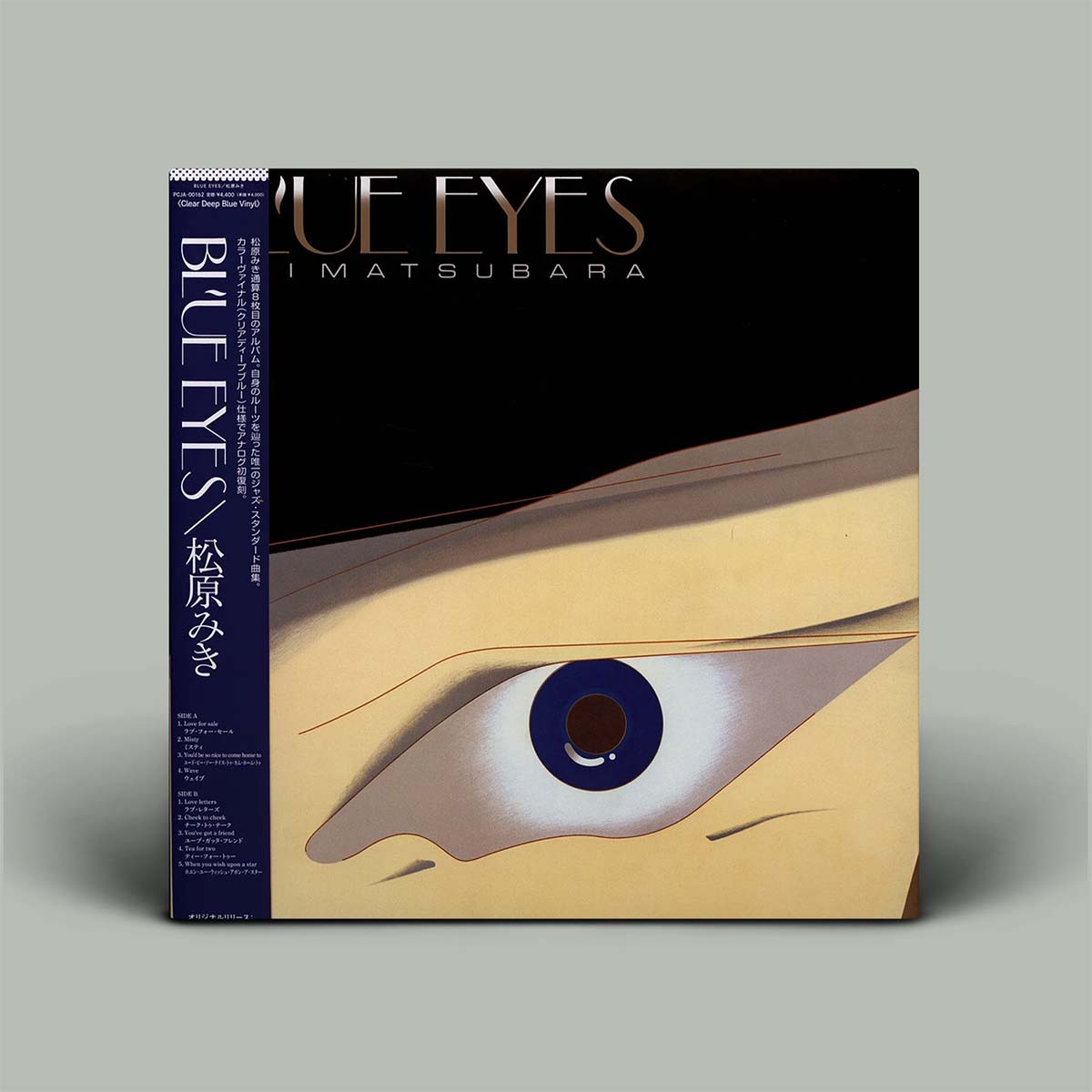 A square album shown on a plain light gray background. The front cover features a stylized eye illustration with a black upper section, beige lower section, and a blue iris.