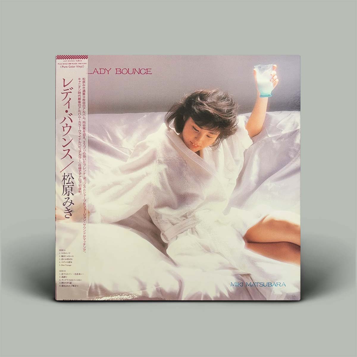 A vinyl record album cover for Lady Bounce, featuring a photograph of her in a white robe on a bed. The Japanese cover is shown standing upright against a neutral gray background.