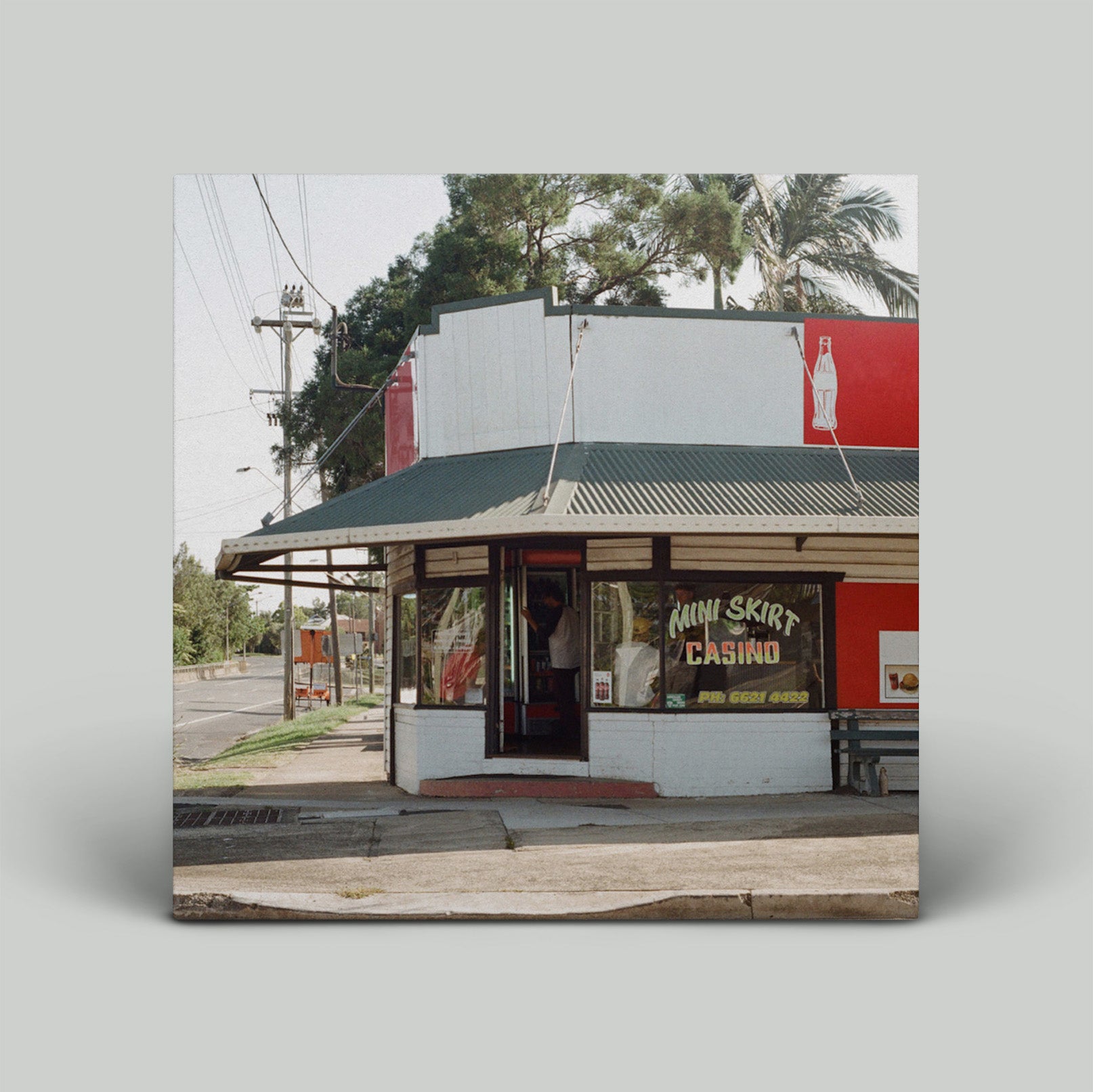 Small building with a green roof and red and white sign on a gray background