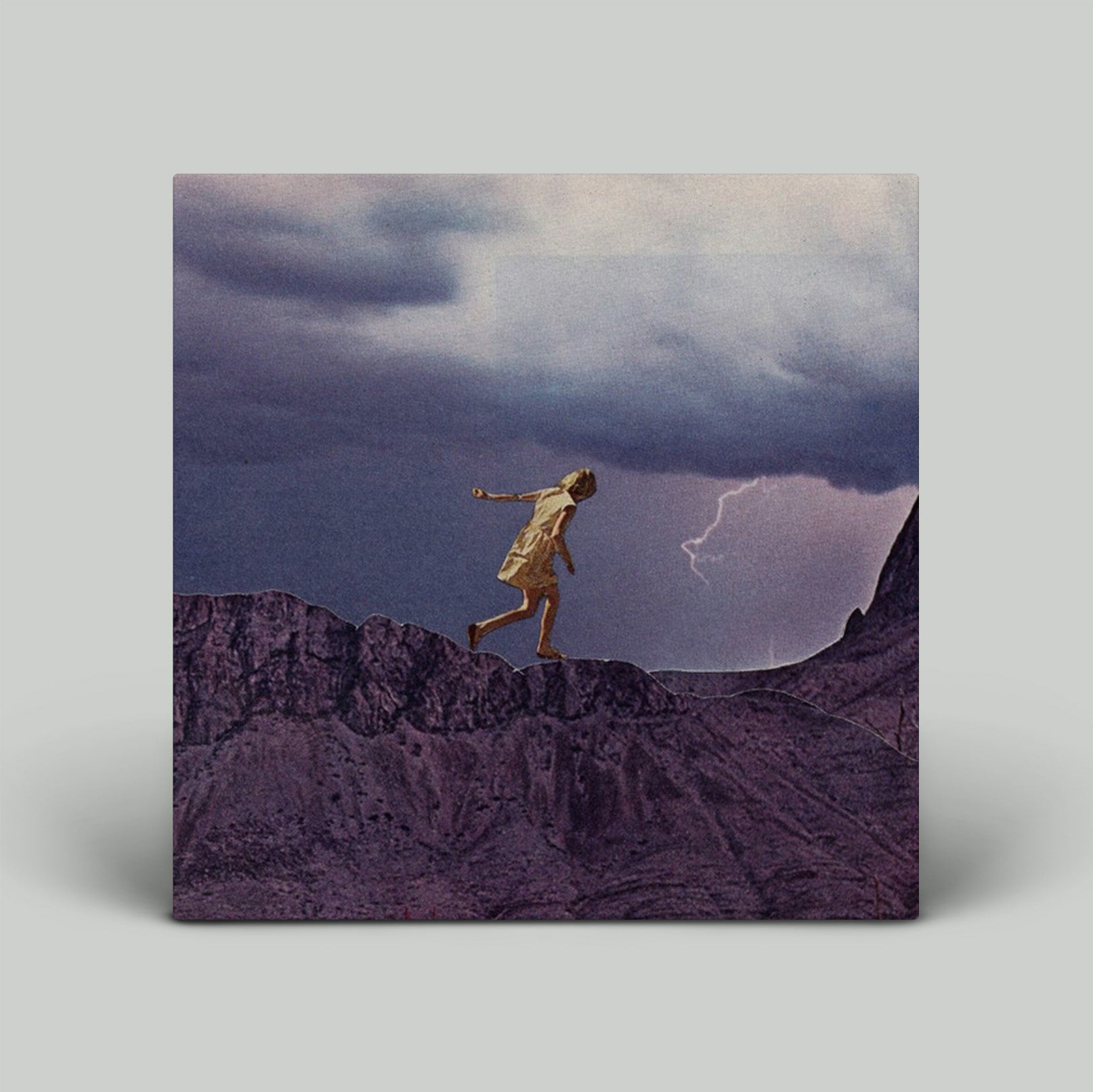 Person walking on a rocky outcrop with a stormy sky and lightning in the background