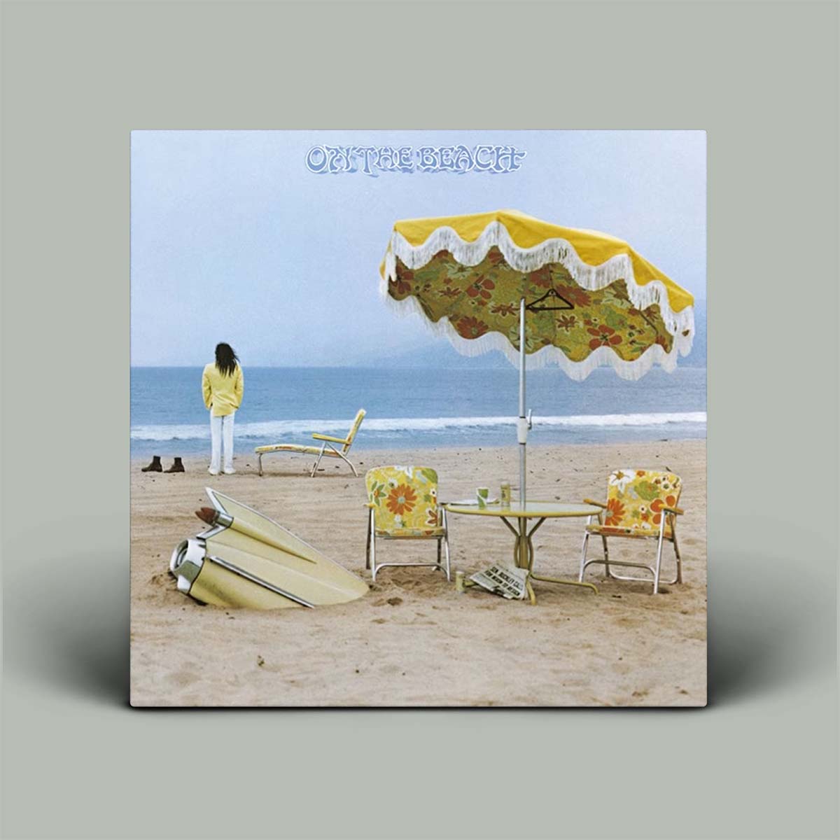 Album cover with a beach scene, table, chairs, and umbrella.